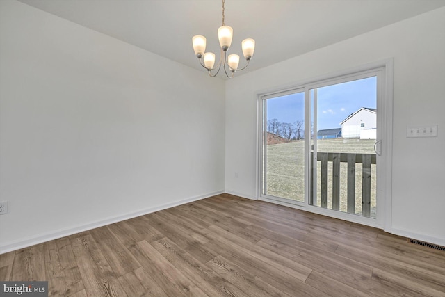 spare room featuring light hardwood / wood-style flooring and a notable chandelier