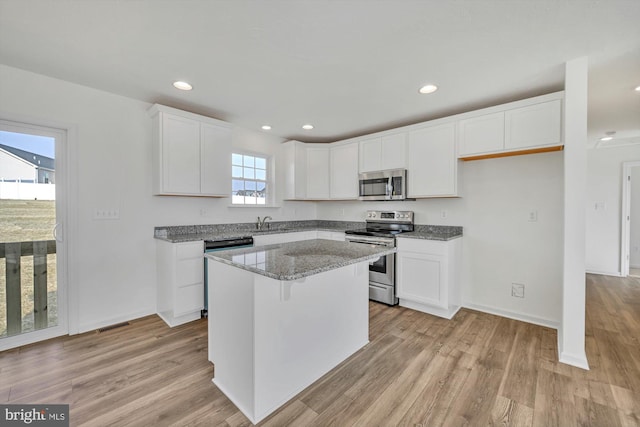 kitchen featuring white cabinets, a center island, stainless steel appliances, and plenty of natural light