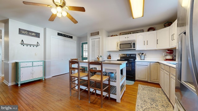 kitchen with white cabinets, light wood-type flooring, stainless steel appliances, and ceiling fan