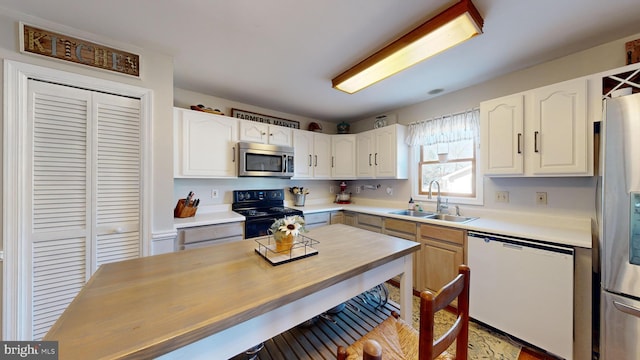 kitchen with appliances with stainless steel finishes, white cabinetry, and sink