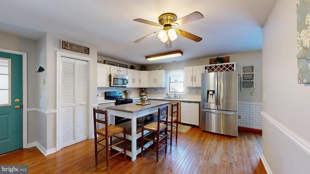 kitchen with wood-type flooring, white cabinetry, sink, and appliances with stainless steel finishes