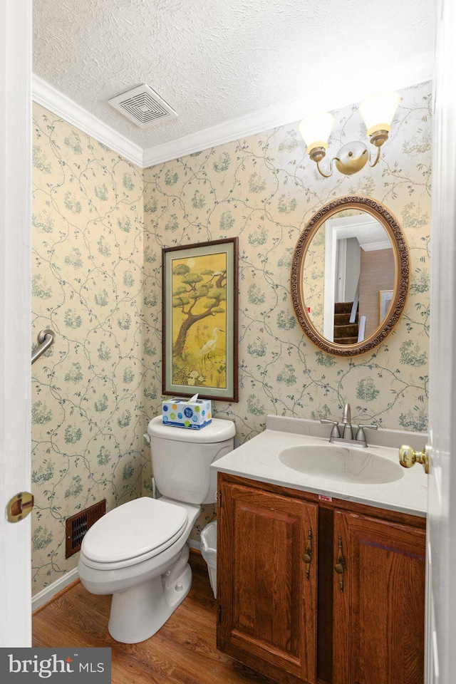 bathroom featuring vanity, a textured ceiling, crown molding, hardwood / wood-style floors, and toilet