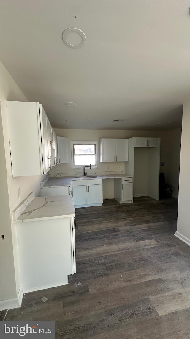 kitchen featuring white cabinets, light stone counters, dark hardwood / wood-style flooring, and sink