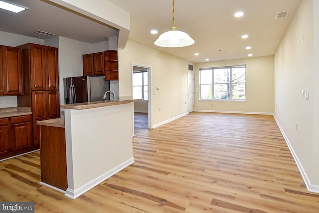 kitchen with stainless steel fridge, pendant lighting, and light wood-type flooring