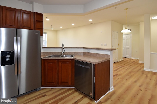 kitchen with stainless steel appliances, light hardwood / wood-style flooring, hanging light fixtures, and sink