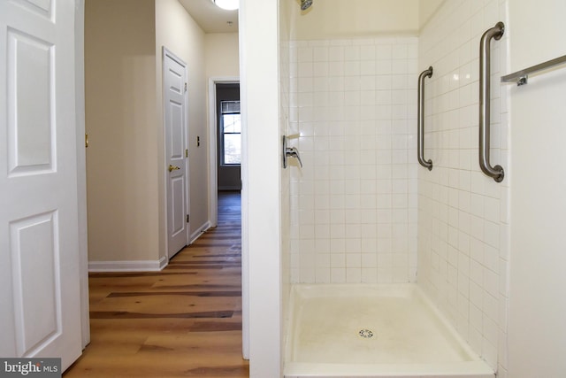 bathroom with wood-type flooring and a tile shower