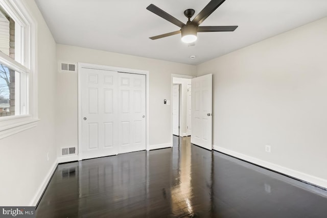 unfurnished bedroom with ceiling fan, a closet, and dark hardwood / wood-style floors