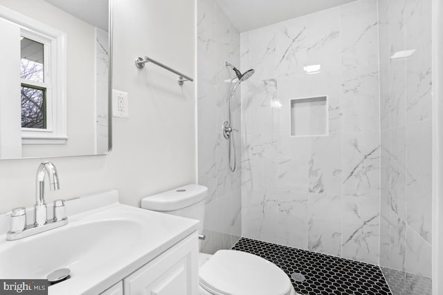 bathroom with tiled shower, vanity, and toilet