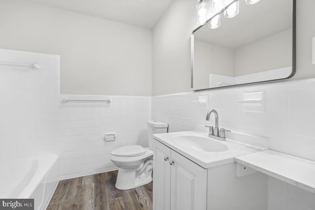 bathroom with hardwood / wood-style floors, vanity, a bathing tub, toilet, and tile walls