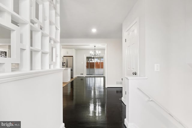 corridor with a notable chandelier and dark hardwood / wood-style flooring