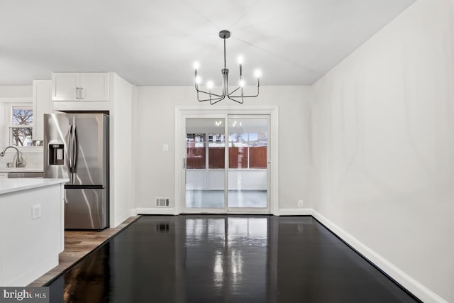 kitchen with hardwood / wood-style floors, an inviting chandelier, stainless steel fridge, decorative light fixtures, and white cabinetry