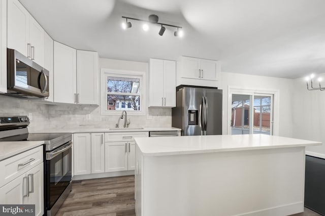 kitchen with backsplash, stainless steel appliances, sink, a center island, and white cabinetry