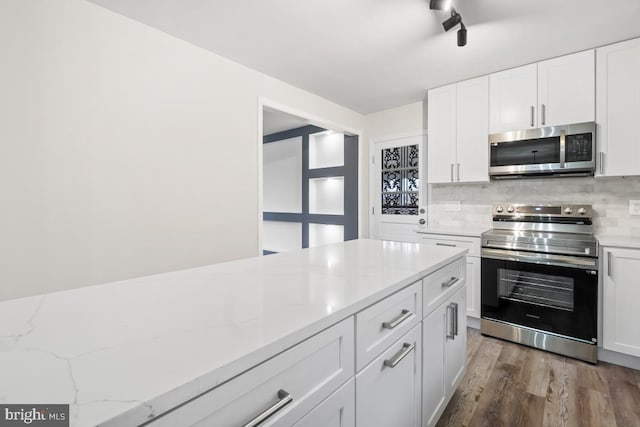 kitchen featuring light stone countertops, white cabinetry, stainless steel appliances, decorative backsplash, and hardwood / wood-style flooring