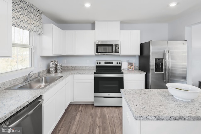 kitchen with appliances with stainless steel finishes, white cabinetry, dark wood-type flooring, and sink