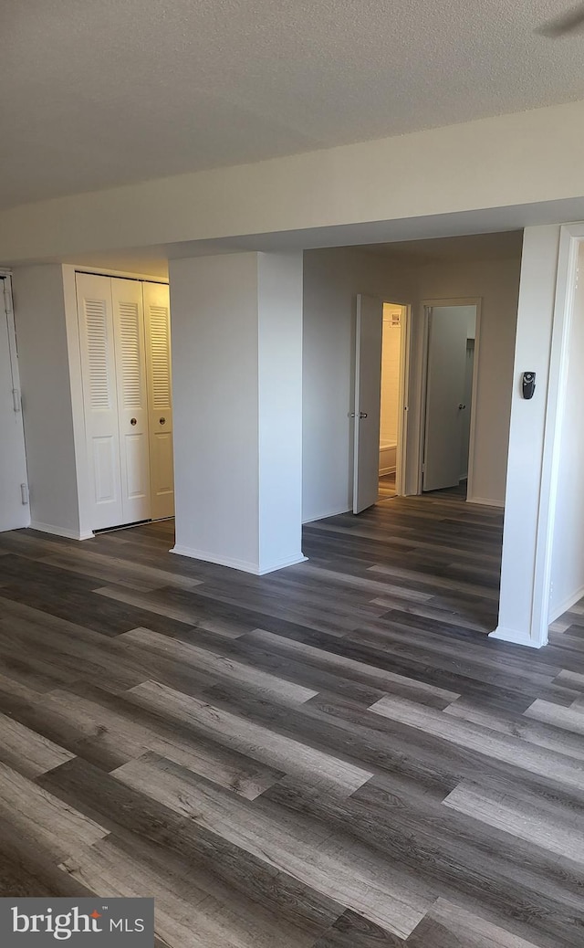 unfurnished room featuring a textured ceiling and dark hardwood / wood-style floors