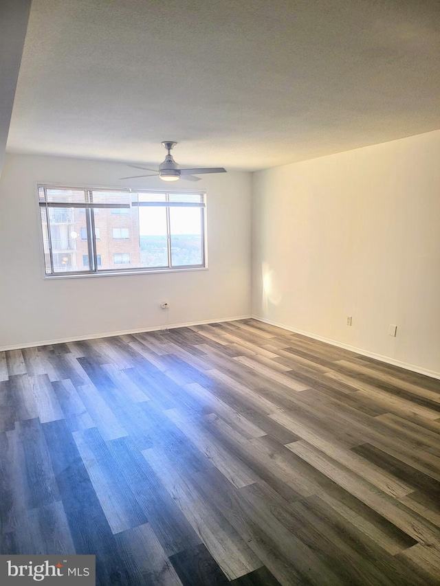 spare room with a textured ceiling, ceiling fan, and dark wood-type flooring