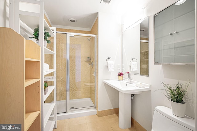 bathroom with tile patterned flooring, toilet, and a shower with door