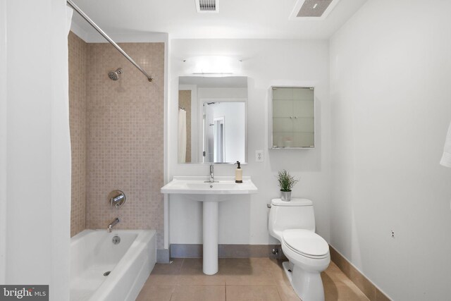 bathroom with tile patterned flooring, tiled shower / bath combo, and toilet