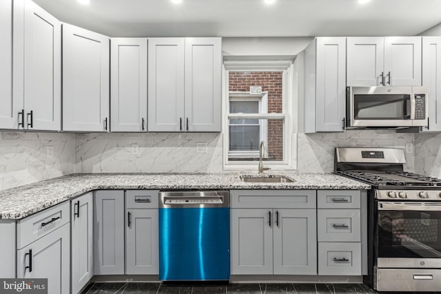 kitchen featuring backsplash, light stone countertops, sink, and appliances with stainless steel finishes