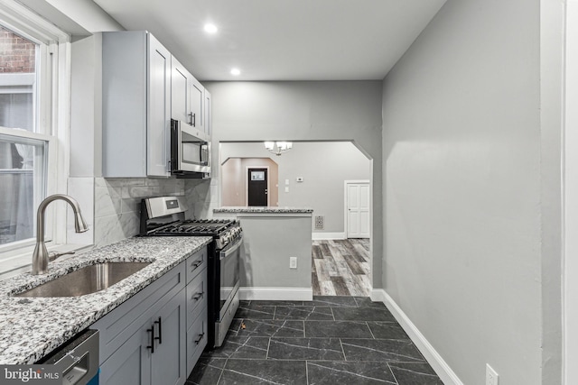 kitchen featuring sink, gray cabinets, light stone countertops, tasteful backsplash, and stainless steel appliances