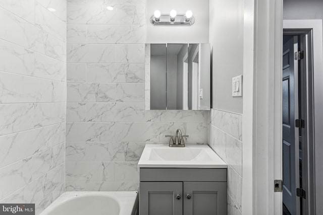 bathroom with a bathing tub, vanity, and tile walls