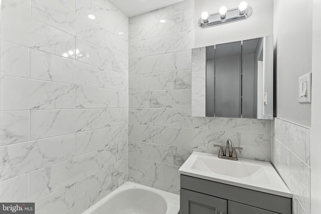 bathroom with a washtub, vanity, and tile walls