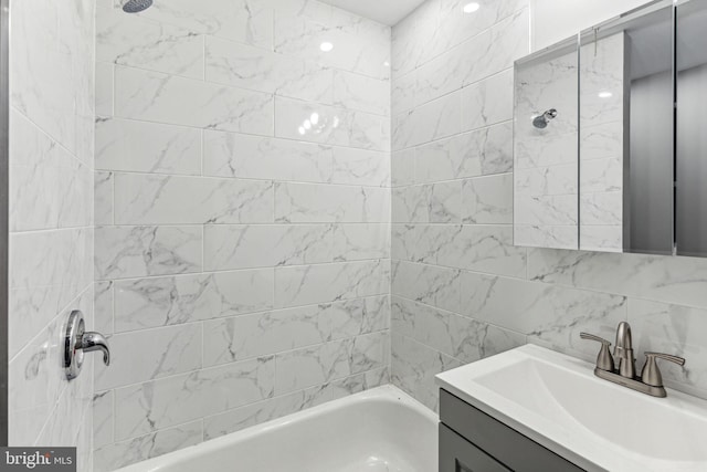 bathroom with vanity, tiled shower / bath, and tile walls