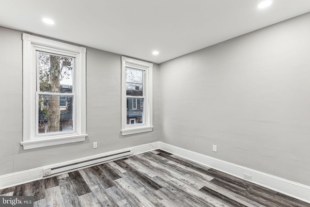 empty room with dark hardwood / wood-style flooring and baseboard heating