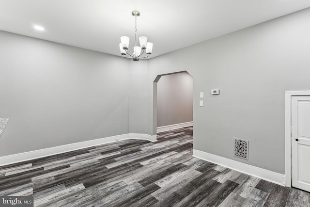 empty room featuring dark hardwood / wood-style floors and an inviting chandelier