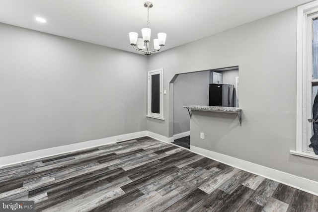 empty room with dark wood-type flooring and a notable chandelier