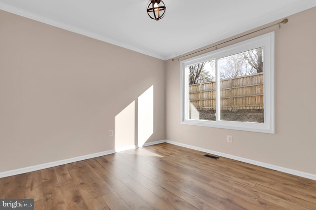 unfurnished room featuring hardwood / wood-style floors and ornamental molding