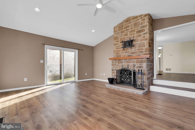 unfurnished living room with ceiling fan, a stone fireplace, wood-type flooring, and vaulted ceiling