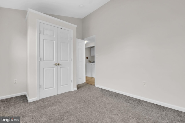 unfurnished bedroom featuring carpet flooring, lofted ceiling, washer / clothes dryer, and a closet