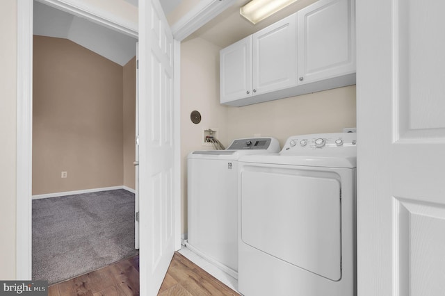 laundry room featuring cabinets, light wood-type flooring, and washing machine and clothes dryer