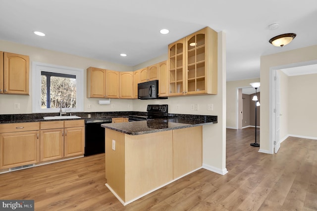 kitchen featuring black appliances, sink, dark stone countertops, light wood-type flooring, and kitchen peninsula