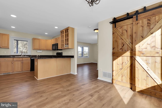 kitchen featuring a barn door, sink, light brown cabinets, and light hardwood / wood-style flooring