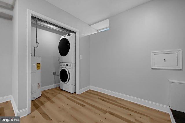 clothes washing area featuring light hardwood / wood-style flooring, stacked washer / drying machine, and water heater