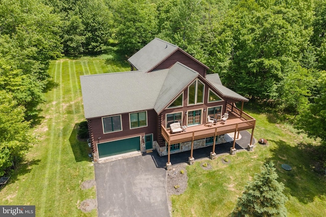 view of front of house featuring stone siding, aphalt driveway, a front yard, and a wooden deck