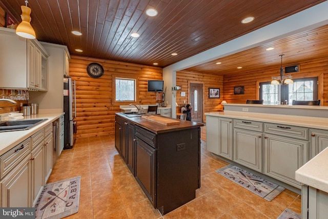 kitchen with wooden ceiling, sink, log walls, and hanging light fixtures