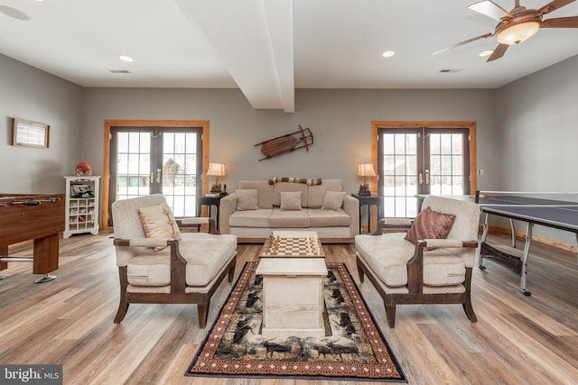 living room featuring a healthy amount of sunlight, light hardwood / wood-style floors, and french doors