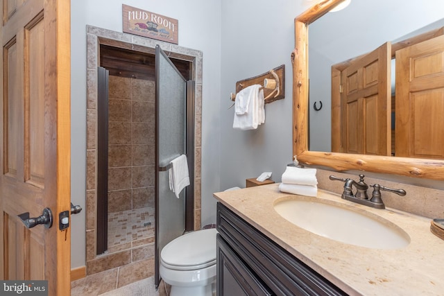 bathroom featuring tile patterned floors, vanity, toilet, and a shower with shower door