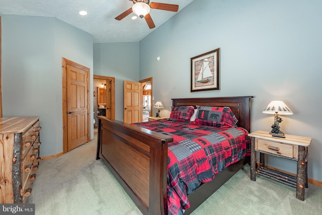 bedroom featuring light carpet, connected bathroom, vaulted ceiling, and ceiling fan