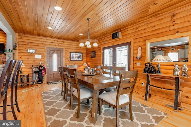 dining room with log walls, light wood-type flooring, and wooden ceiling