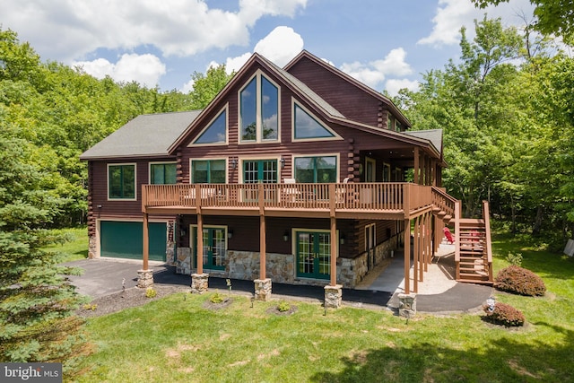 rear view of property with french doors, a yard, a deck, and a garage