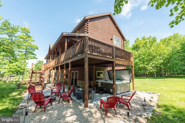 back of property with a patio, a hot tub, a lawn, and a wooden deck