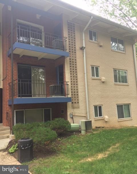 rear view of house with central AC unit and a lawn