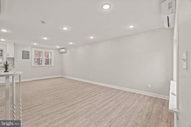 interior space with a wall mounted air conditioner, electric panel, and light hardwood / wood-style flooring