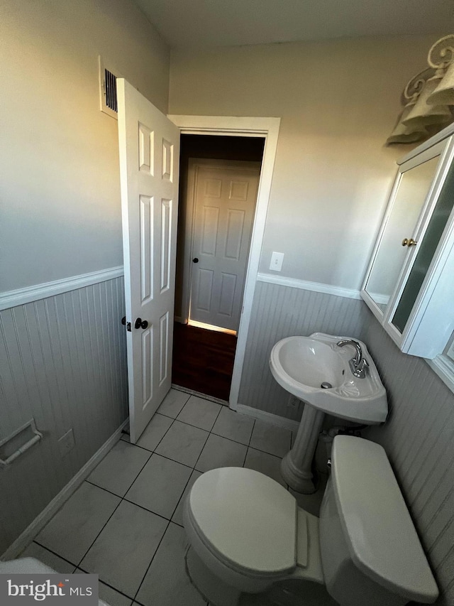 bathroom featuring tile patterned flooring, toilet, and wooden walls