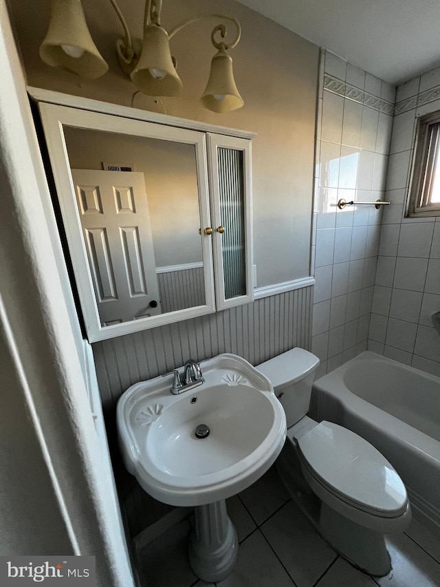 bathroom with a bathing tub, sink, toilet, and tile patterned floors