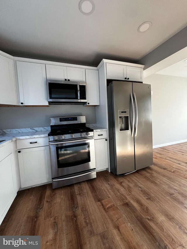 kitchen with dark hardwood / wood-style floors, light stone countertops, white cabinetry, and stainless steel appliances